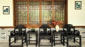 A traditional room with a large window, a table with chairs, and a vase with flowers. - Mufu Leisure Mountian Resort (Muchuan)
