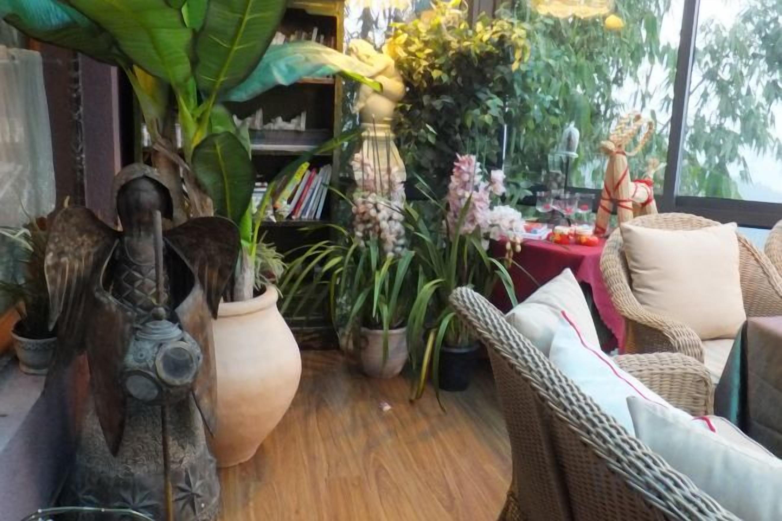 A room with wicker furniture, a large potted plant, and a statue.