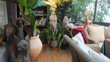 A room with wicker furniture, a large potted plant, and a statue.