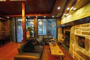 A cozy interior with a stone fireplace, leather sofa, and a wooden table. - Taole Forest Hostel (Chongqing)