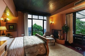 A bedroom with a large bed, a chair, a fireplace, and a view of greenery outside. - Taole Forest Hostel (Chongqing)