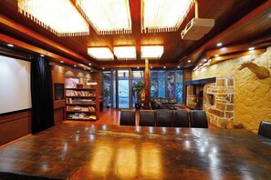 A spacious room with a large wooden table, a fireplace, and a bookshelf. - Taole Forest Hostel (Chongqing)
