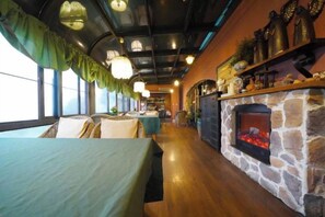 A cozy interior with a stone fireplace, wooden tables, and a long corridor with windows. - Taole Forest Hostel (Chongqing)