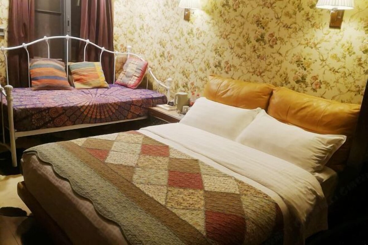 A hotel room with a bed, a smaller bed, and a nightstand with a lamp.