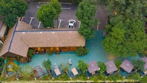 An aerial view of a resort with a large building, outdoor seating, and a swimming pool surrounded by lush greenery. - Taole Forest Hostel (Chongqing)