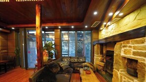 A cozy interior with a stone fireplace, wooden ceiling, and a seating area with a sofa and table. - Taole Forest Hostel (Chongqing)