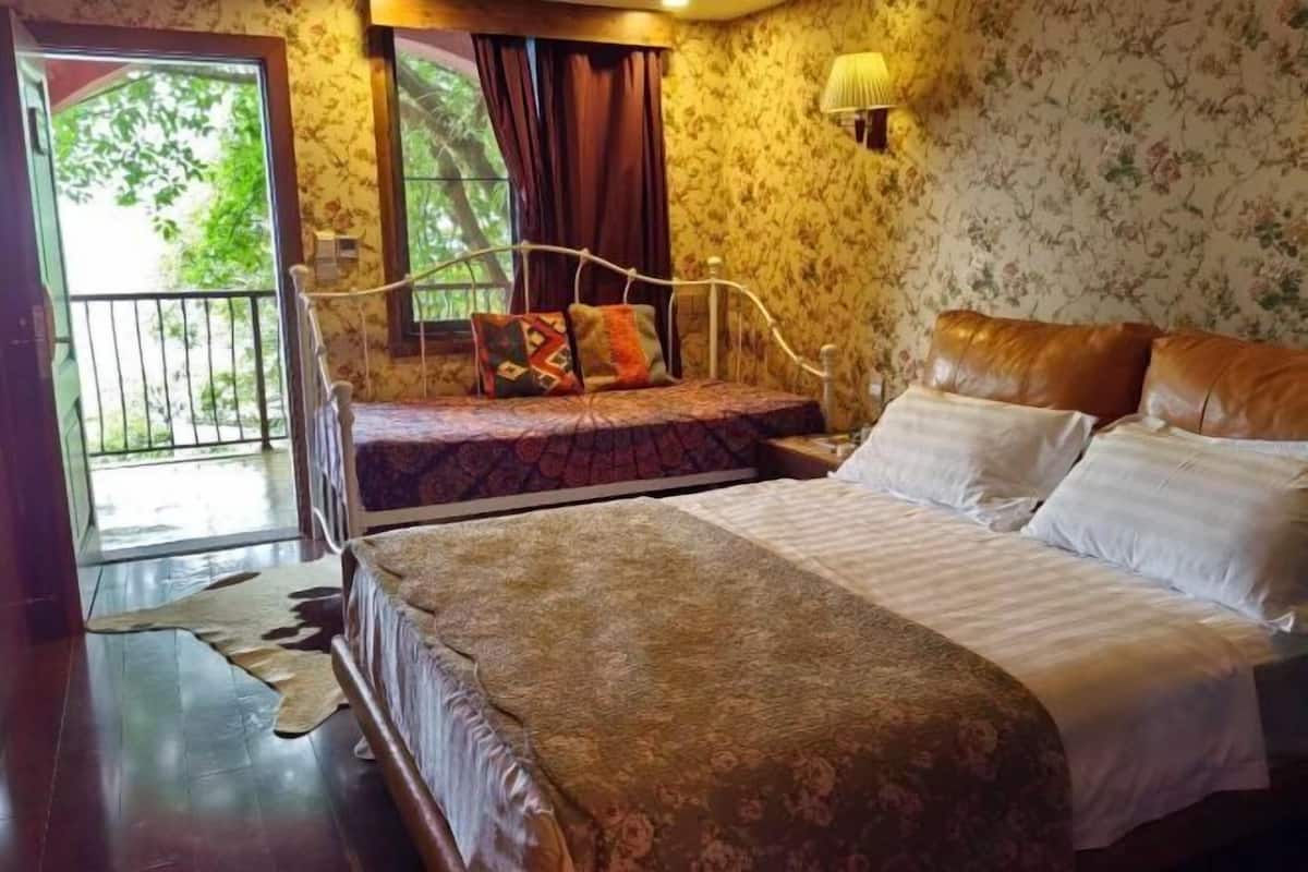 A bedroom with a bed, a nightstand, a lamp, and a window with curtains.