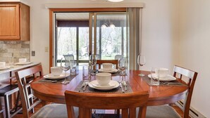 A dining area with a wooden table set for six, surrounded by chairs.