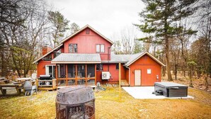 A red two-story house with a covered porch, a small shed, and a fire pit in the yard.
