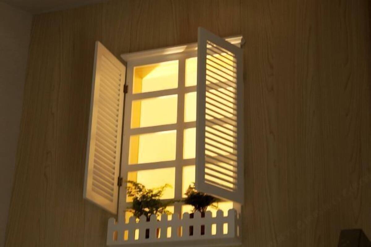 Een raam met open luiken, een witte picket fence en uitzicht op groen.