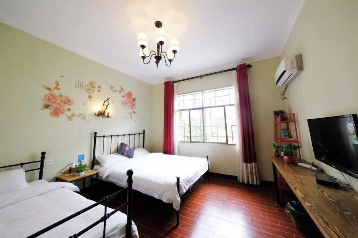 Een slaapkamer met twee bedden, een televisie, een kroonluchter, een raam met gordijnen en een wanddecoratie.