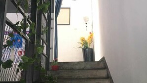 A staircase leading to a door with a framed picture and a wall-mounted light fixture. - Huashijian Youth Hostel (Hengyang)