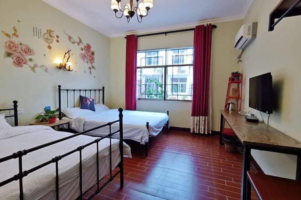 Een kamer met twee bedden, een televisie en een raam met rode gordijnen.