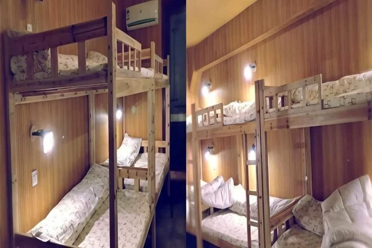 Tweepersoonsbed met houten leuningen en hoofdborden, houten lambrisering en een klein plankje met een lamp.