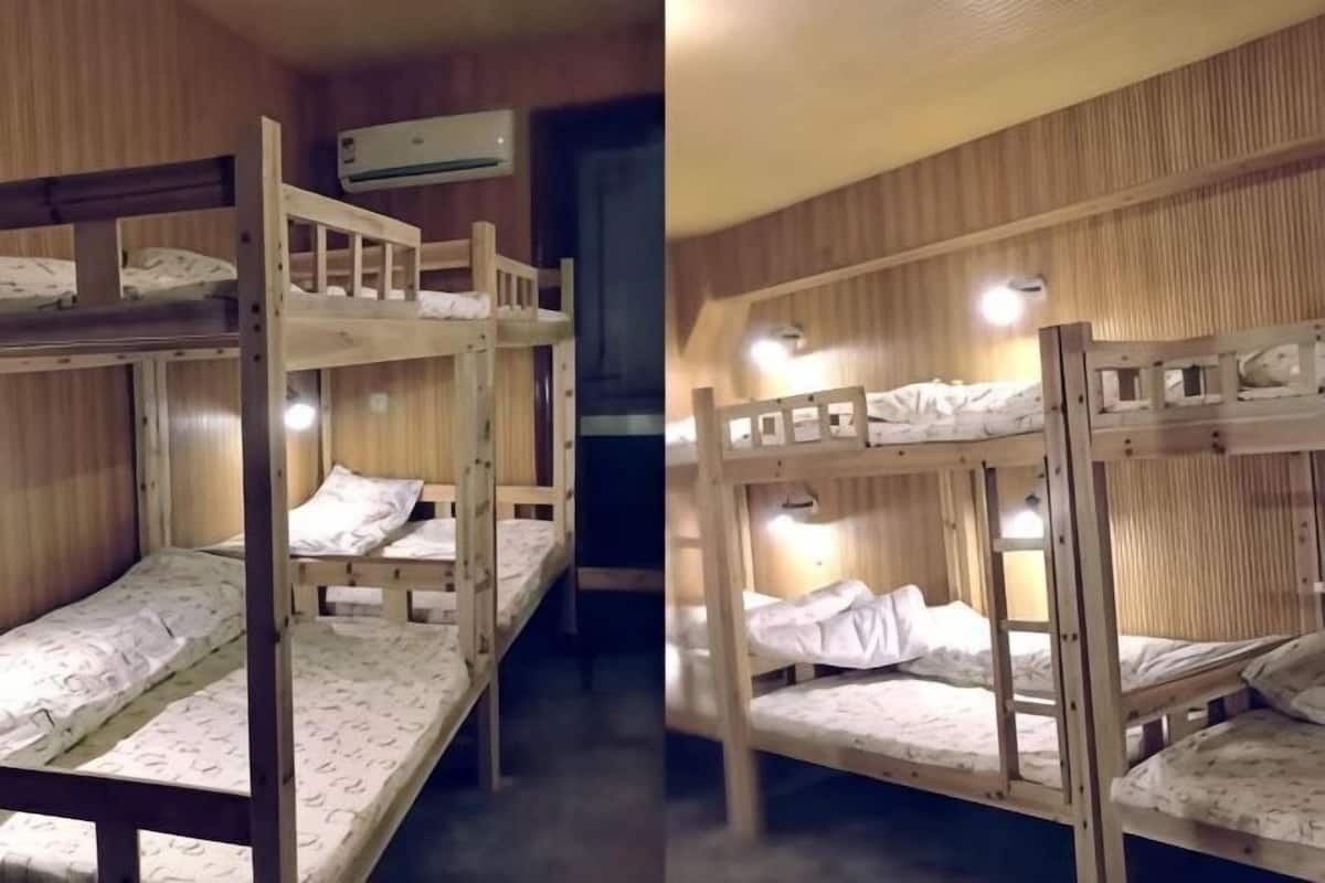 Een slaapkamer met stapelbed, houten wanden, een plafondventilator en een raam.