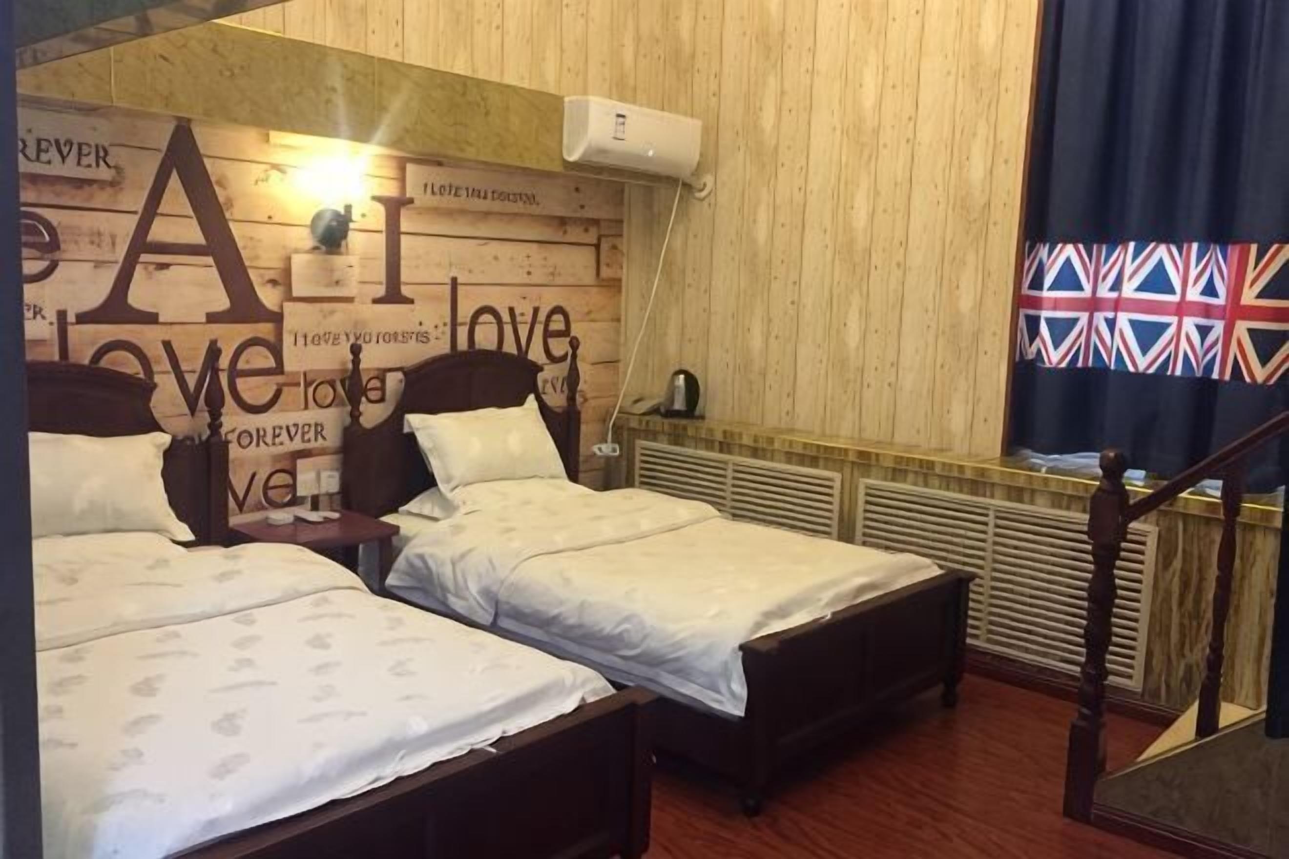 A room with two beds, a wooden headboard with text, a radiator, and a flag.