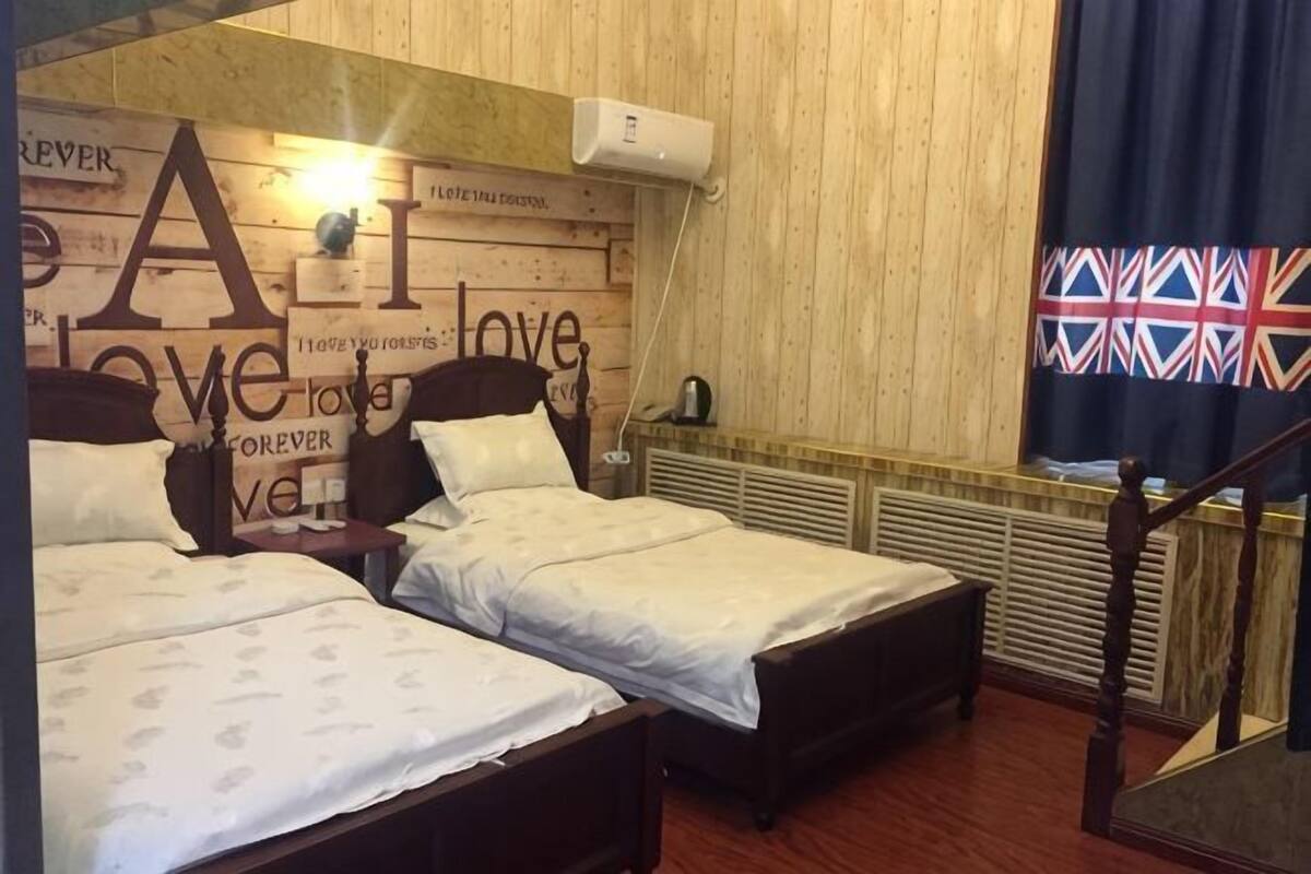 A room with two beds, a wooden headboard with text, a radiator, and a flag.