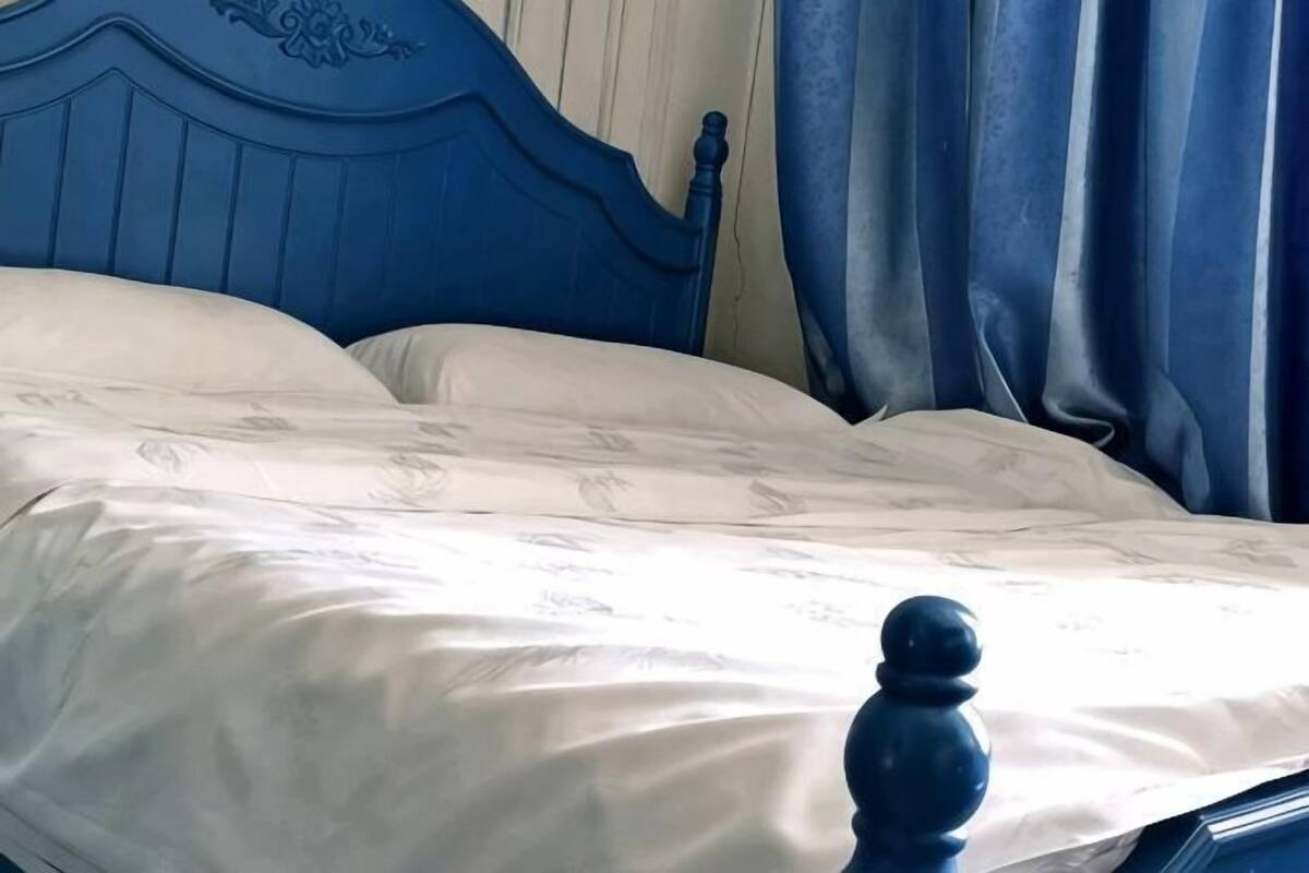 A bed with a blue headboard, white bedding, and a single round object on the bed.