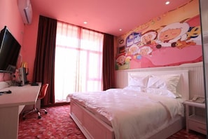 A bedroom with a bed, a desk, a chair, a television, and a wall with cartoon characters. - Xintian'e Boutique Hotel (Ulanhot)