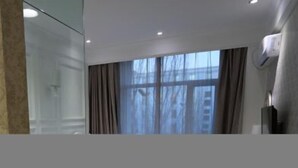 A modern hotel room with a large window, a mirror, and a door. - Xintian'e Boutique Hotel (Ulanhot)