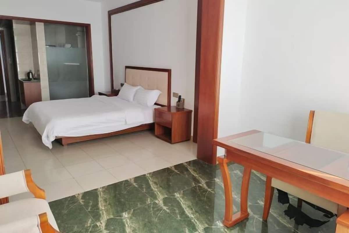 Une chambre d’hôtel avec un lit, une table de chevet en bois, une table et une chaise.