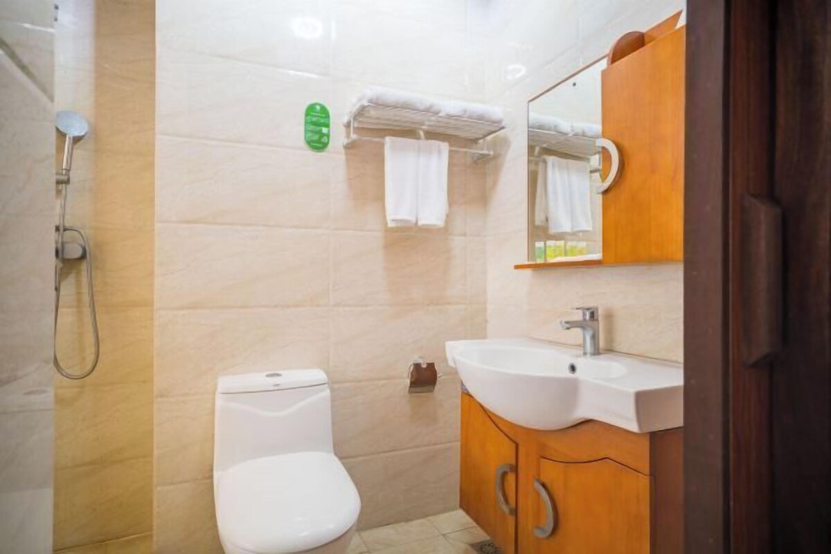 Une salle de bain comprenant des toilettes, un lavabo, un miroir et une douche.