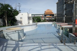 Zona de piscina con diseño curvo, rodeada por un muro bajo y una barandilla de metal.