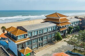 Un hotel costero de estilo arquitectónico tradicional, con un edificio destacado de techo a la vista y vistas a la playa.