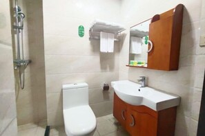 A bathroom with a toilet, sink, mirror, and towel rack. - Xinsha Hotel (Zhanjiang)