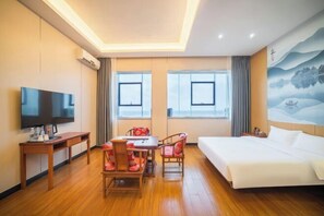 Una habitación de hotel con cama, televisor, escritorio y mesa de comedor con sillas.