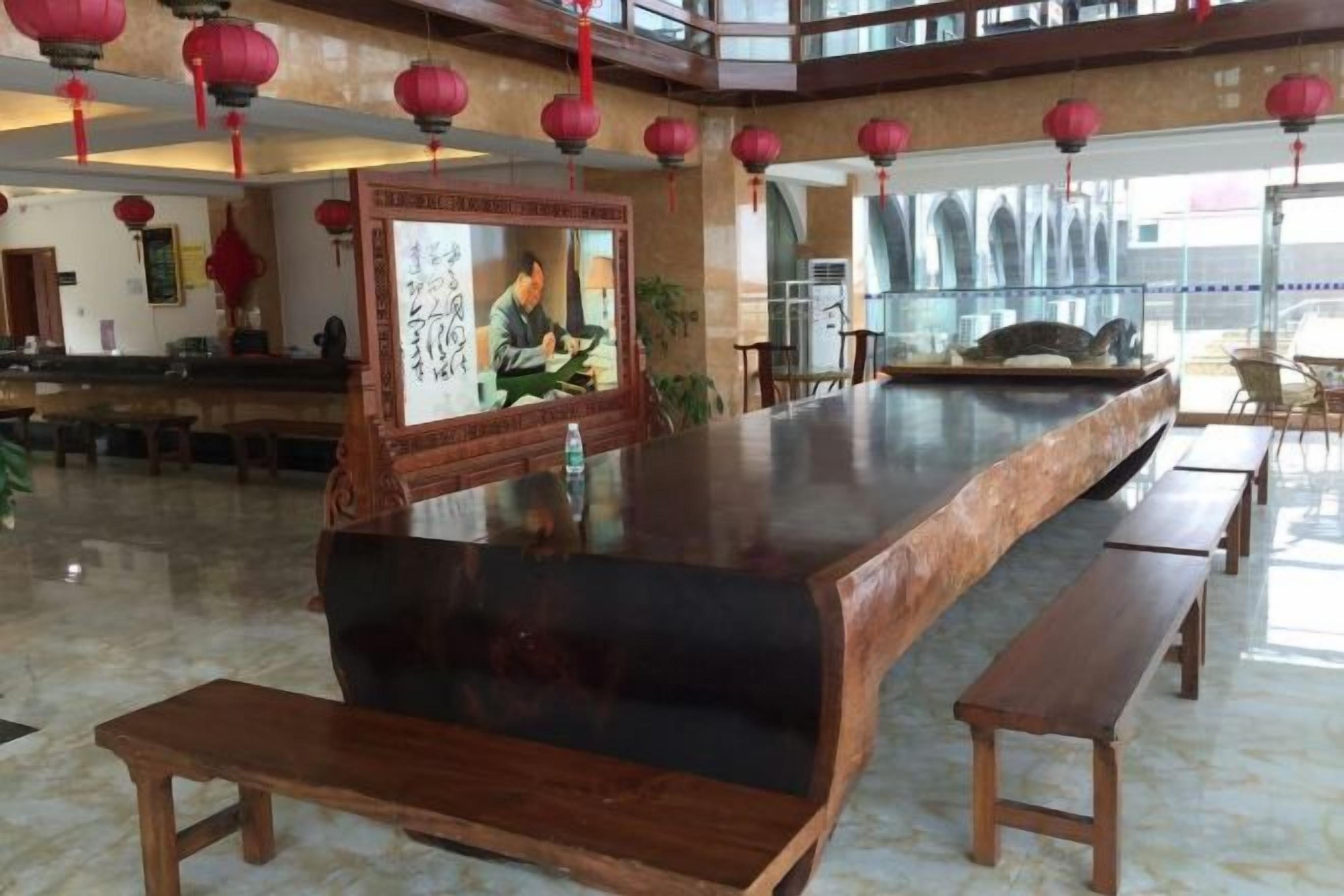 A spacious lobby with a long reception desk, wooden benches, and red lanterns.