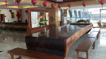 A spacious lobby with a long reception desk, wooden benches, and red lanterns.