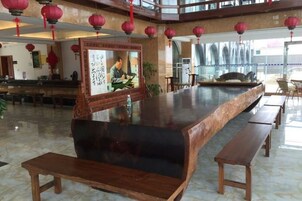 Un vestíbulo amplio con una larga recepción, bancos de madera y faroles rojos.