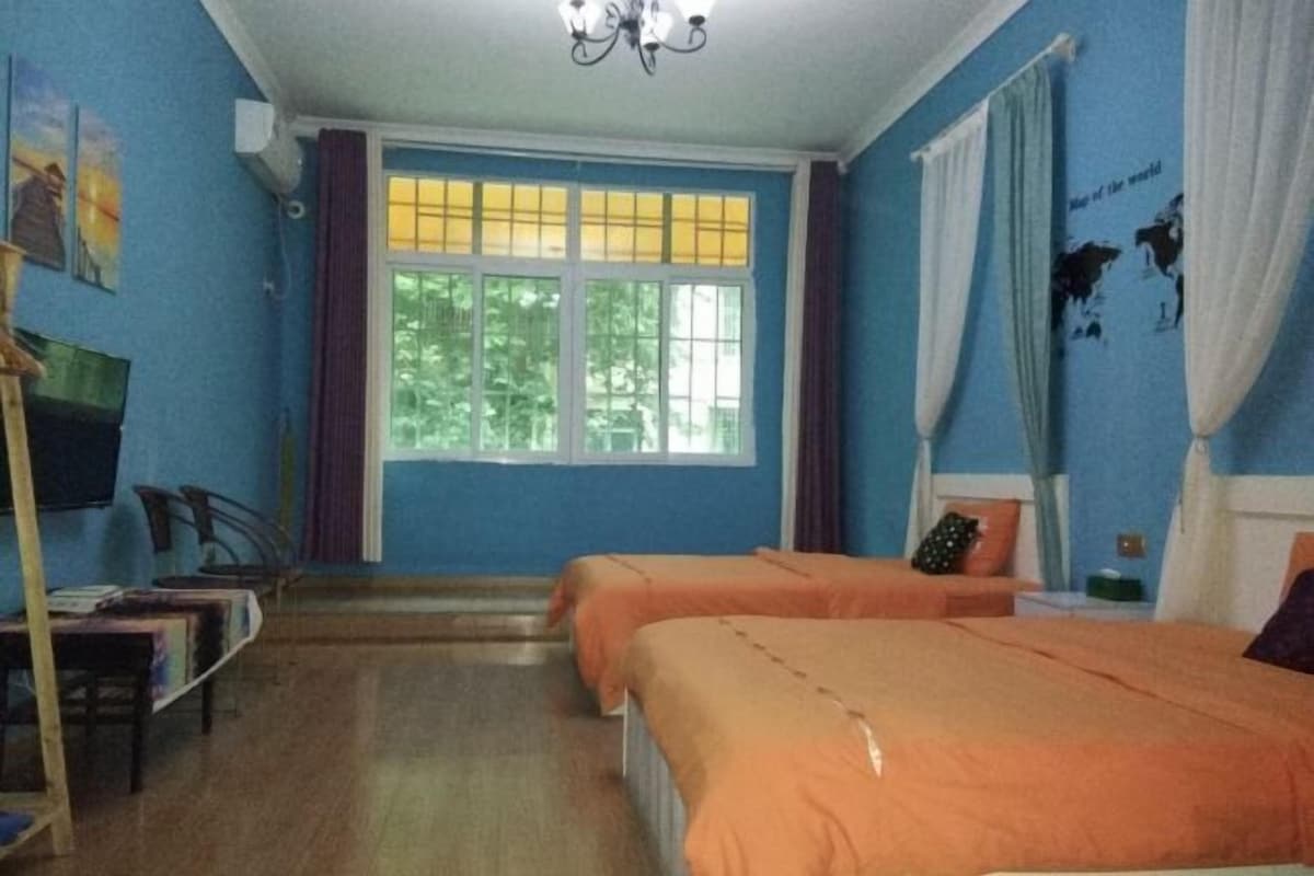 Una habitación con dos camas, televisión y ventana con cortinas.
