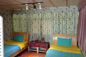 Una habitación con dos camas, una mesa con mantel floral y una cortina estampada.