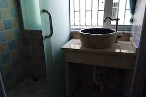 A bathroom with a sink, a window with bars, and a towel rack. - manmancoffee (Zixing)