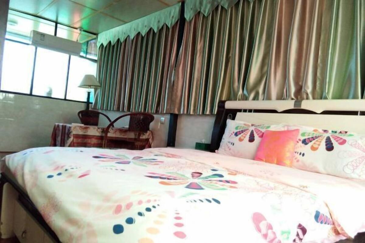 Ein Hotelzimmer mit Bett, Vorhängen, einer Lampe und einem Fenster.