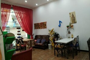 Un salon comprenant un canapé, une table à manger, des chaises et une fenêtre avec des rideaux rouges.