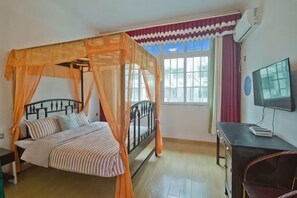 Une chambre à coucher avec un lit à baldaquin, un bureau, une chaise et un téléviseur.