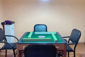 Une pièce avec une table à carreaux verts, quatre chaises noires et un meuble blanc.