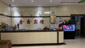 A hotel reception area with a reception desk, clocks, and a TV screen. - Jinxinbinguan (Shizong)