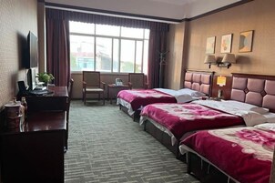Habitación de hotel con dos camas, un escritorio con computadora, una silla y una ventana con cortinas.