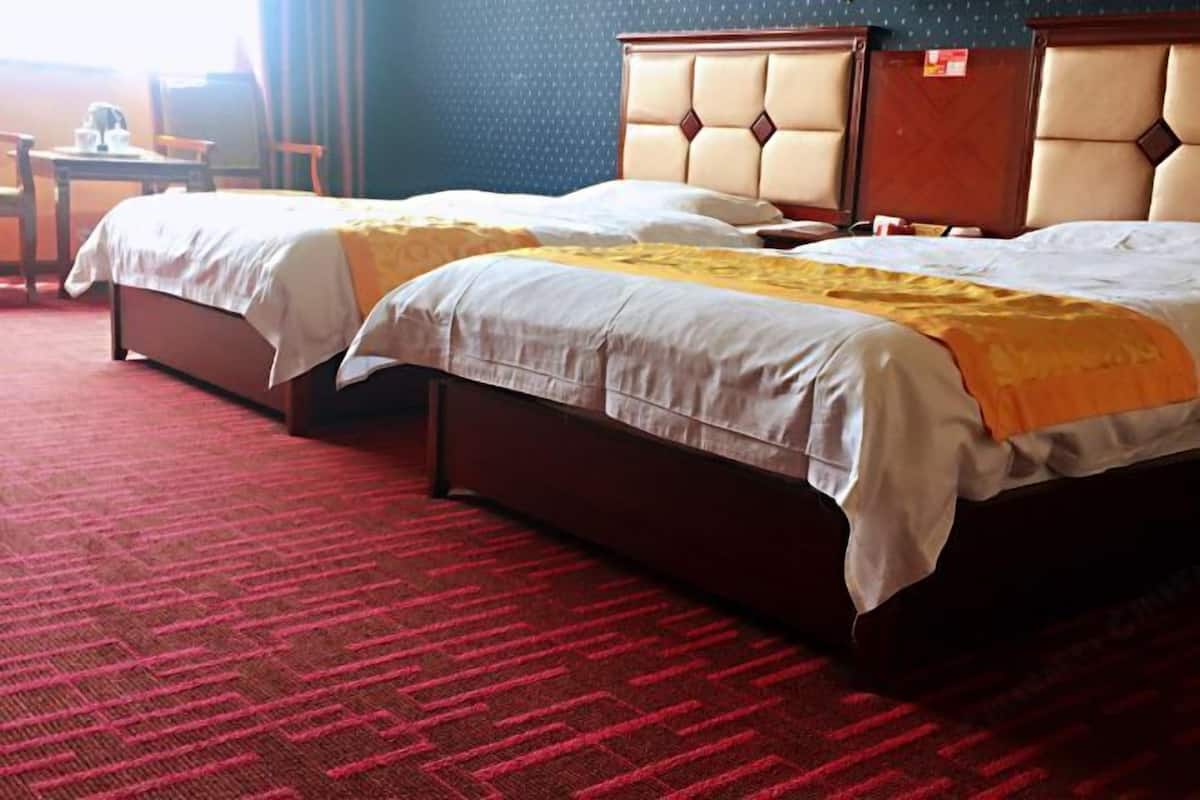 A hotel room with two beds, a red carpet, and a small table with chairs.