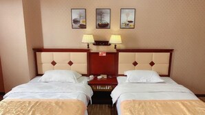 Habitación de hotel con dos camas, cabecera de madera, mesita de noche y tres lámparas fijadas a la pared.