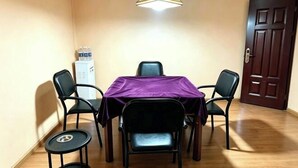 Un comedor con una mesa, cuatro sillas, un mantel púrpura, una lámpara colgante y una puerta al fondo.