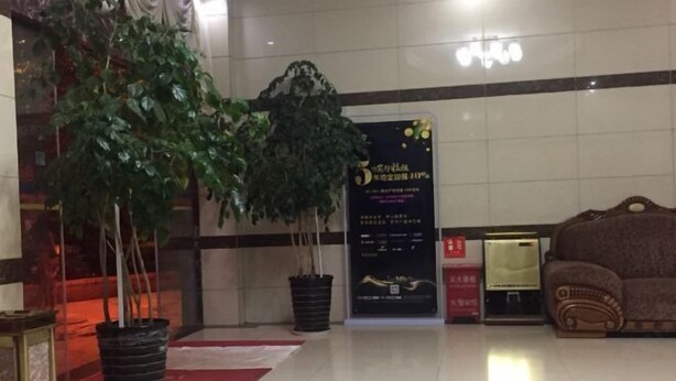 A lobby with a large potted plant, a reception desk, and a wall with a sign. - Jinxinbinguan (Shizong)
