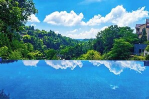 Una piscina blu cristallina che riflette alberi e un edificio.