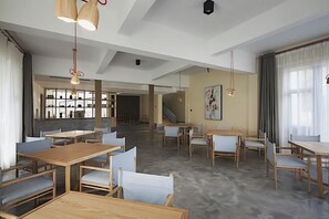 A spacious dining area with wooden tables and chairs, a staircase in the background, and pendant lighting. - Fuzhou Xin'an Office, Shibuya Villa (Fuzhou)