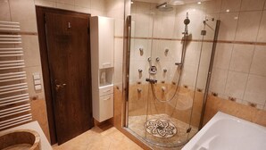 Une salle de bain moderne dotée d’une douche à parois de verre, d’une grande baignoire et d’un meuble-lavabo avec un évier et un miroir.