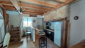 Une cuisine avec des poutres en bois, un mur en pierre, un four à micro-ondes et un réfrigérateur.